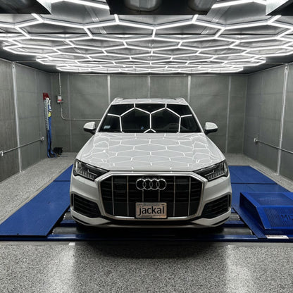 HS Tuning white Audi Q7 SUV on a dyno machine with hexagonal ceiling lighting in a professional workshop
