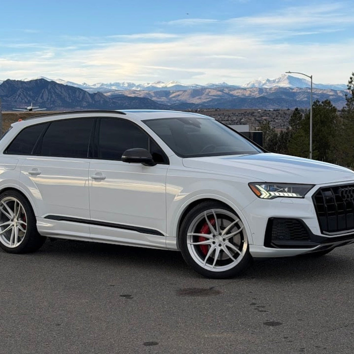 HS Tuning performance white Audi SQ7 SUV with custom wheels parked against a scenic mountain backdrop.